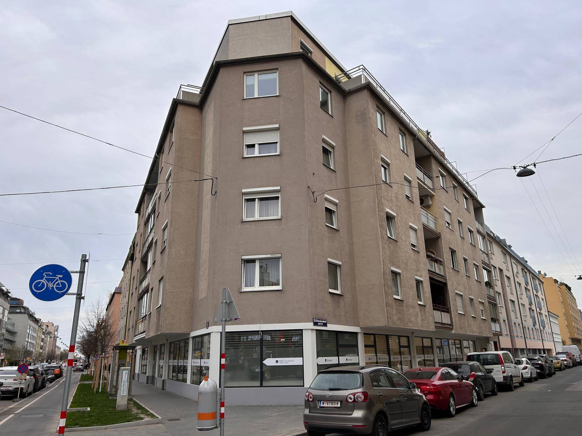 Mehrstöckiges Eckgebäude mit moderner Fassade und vielen Fenstern in einer städtischen Umgebung.