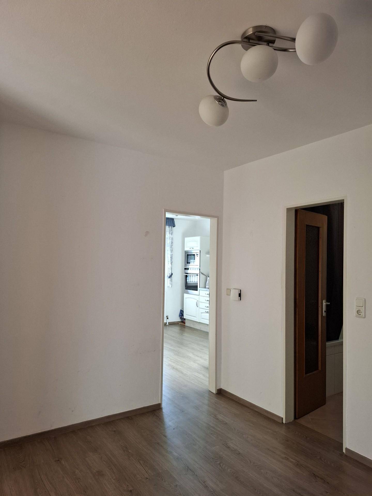Heller Flur mit Laminatboden und Zugang zu verschiedenen Zimmern, inklusive der Küche.