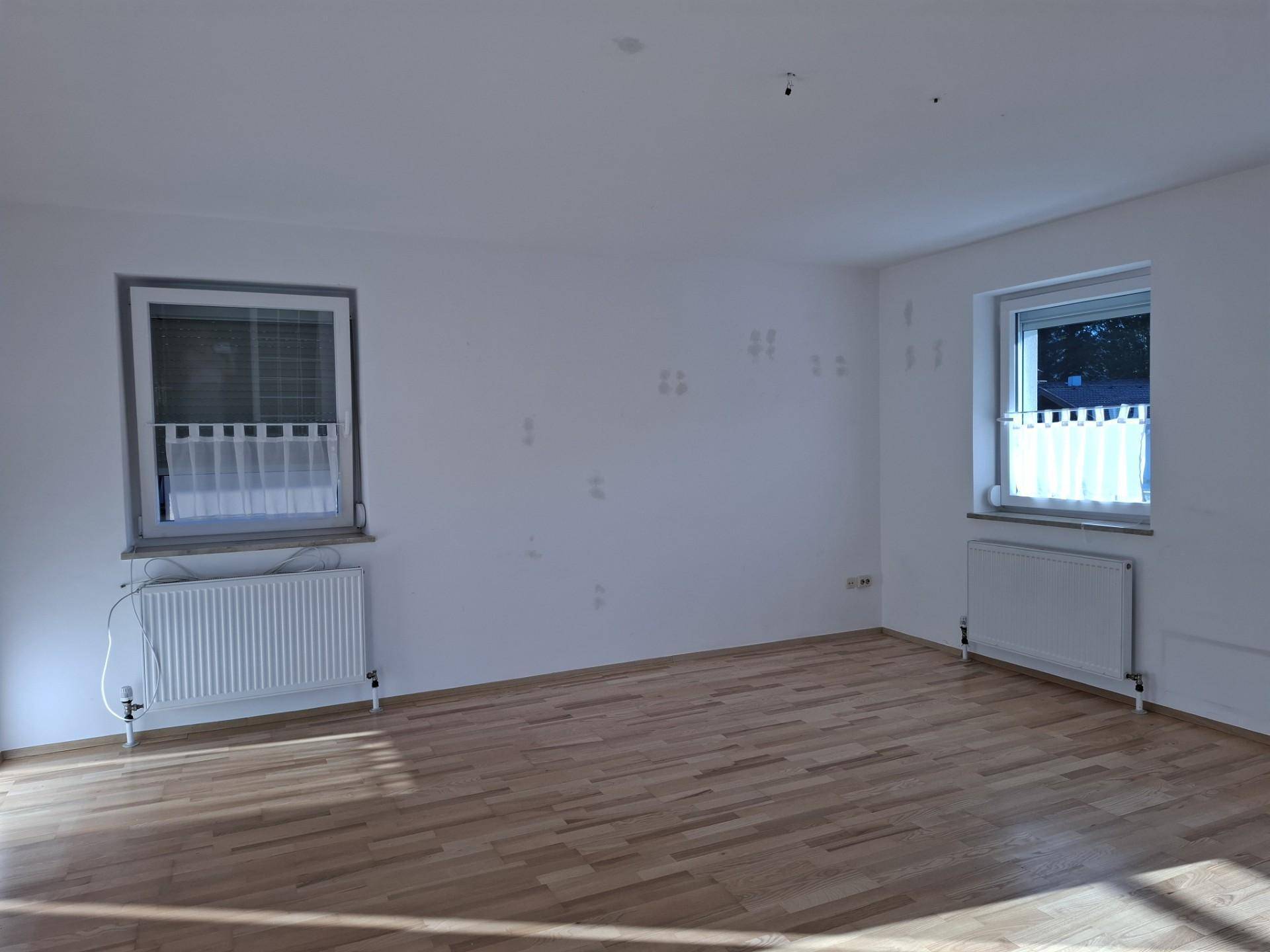 Geräumiges, helles Zimmer mit Holzboden und zwei Fenstern, ideal für individuelle Gestaltung.