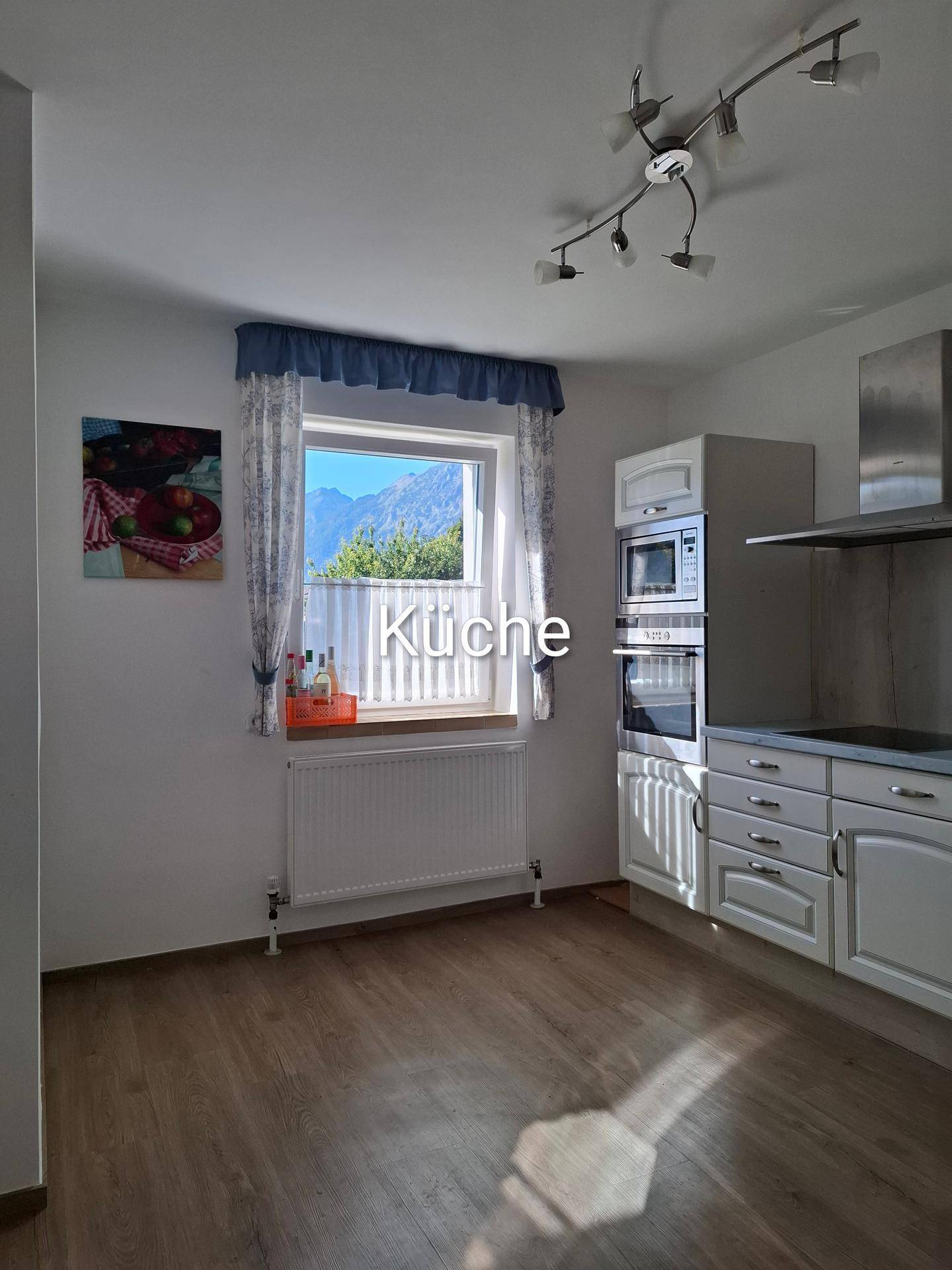Funktionale Küche mit Einbauschränken, integrierten Geräten und Bergblick durch das Fenster.