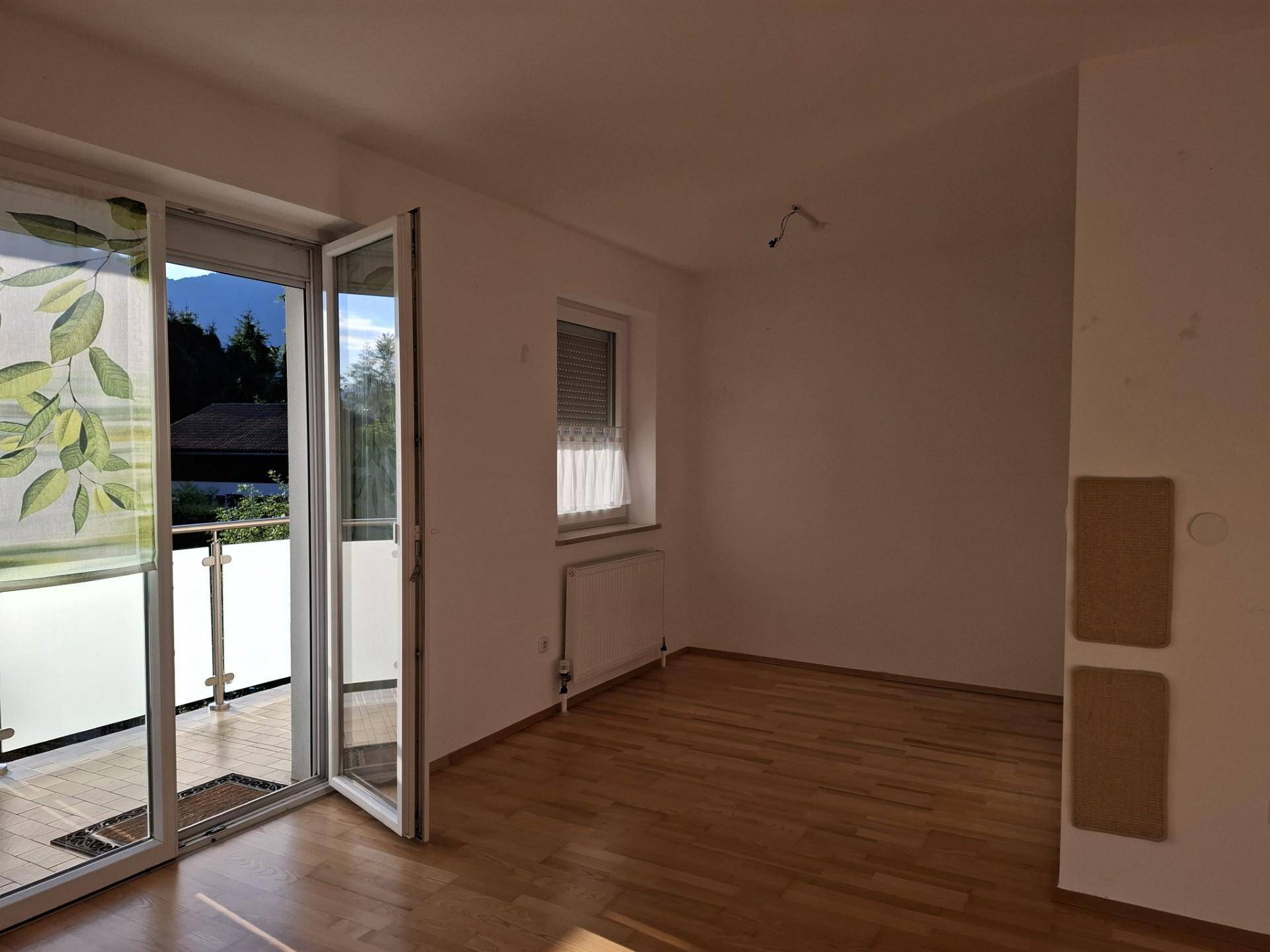 Helles Zimmer mit Holzboden, weißen Wänden und direktem Zugang zu einem Balkon.