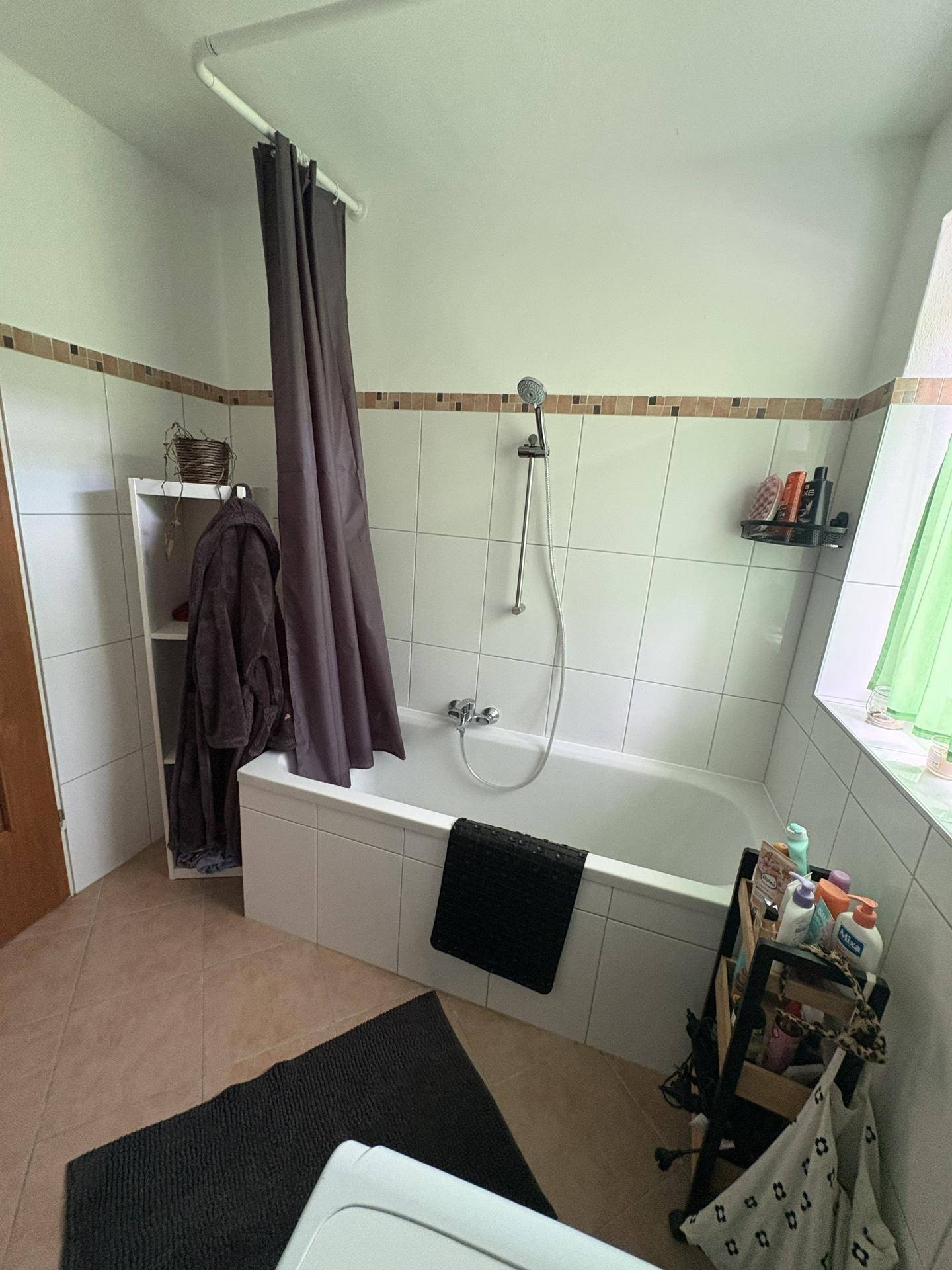 Badezimmer mit Badewanne, Duschvorhang und einem Fenster für Tageslicht.