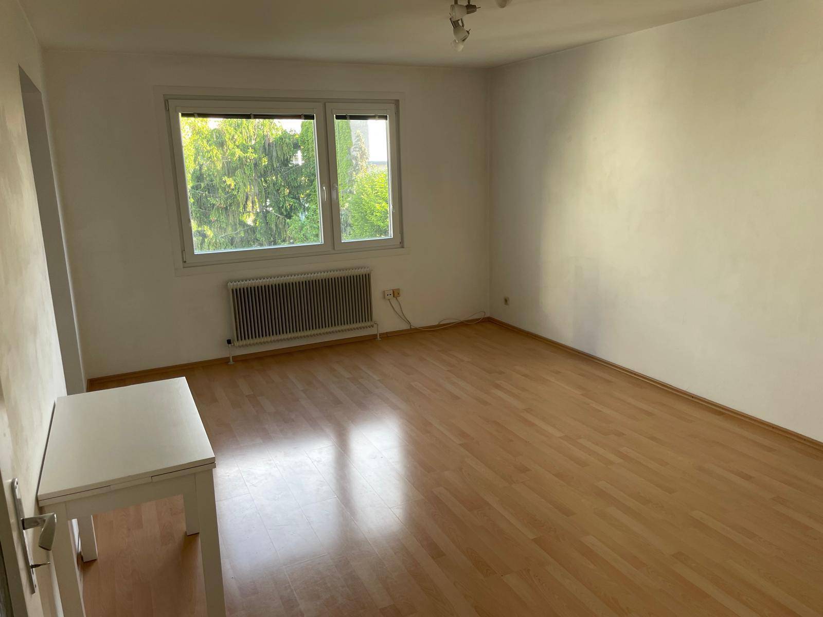 Helles Zimmer mit Parkettboden, großen Fenstern und Blick ins Grüne, ideal als Schlaf- oder Arbeitszimmer.