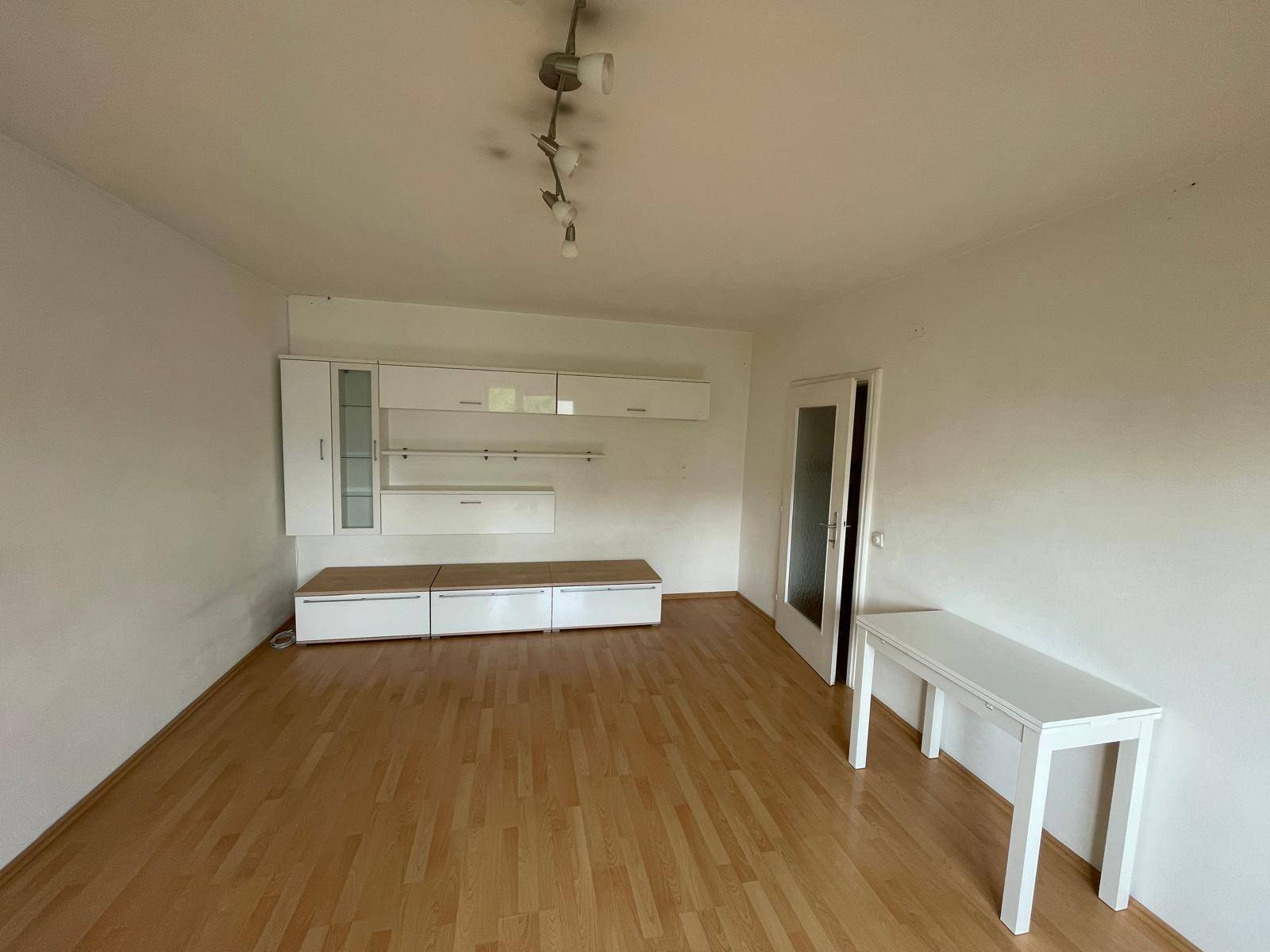Leeres Zimmer mit hellem Parkettboden und einer modernen weißen Schrankwand, bereit zur individuellen Gestaltung.