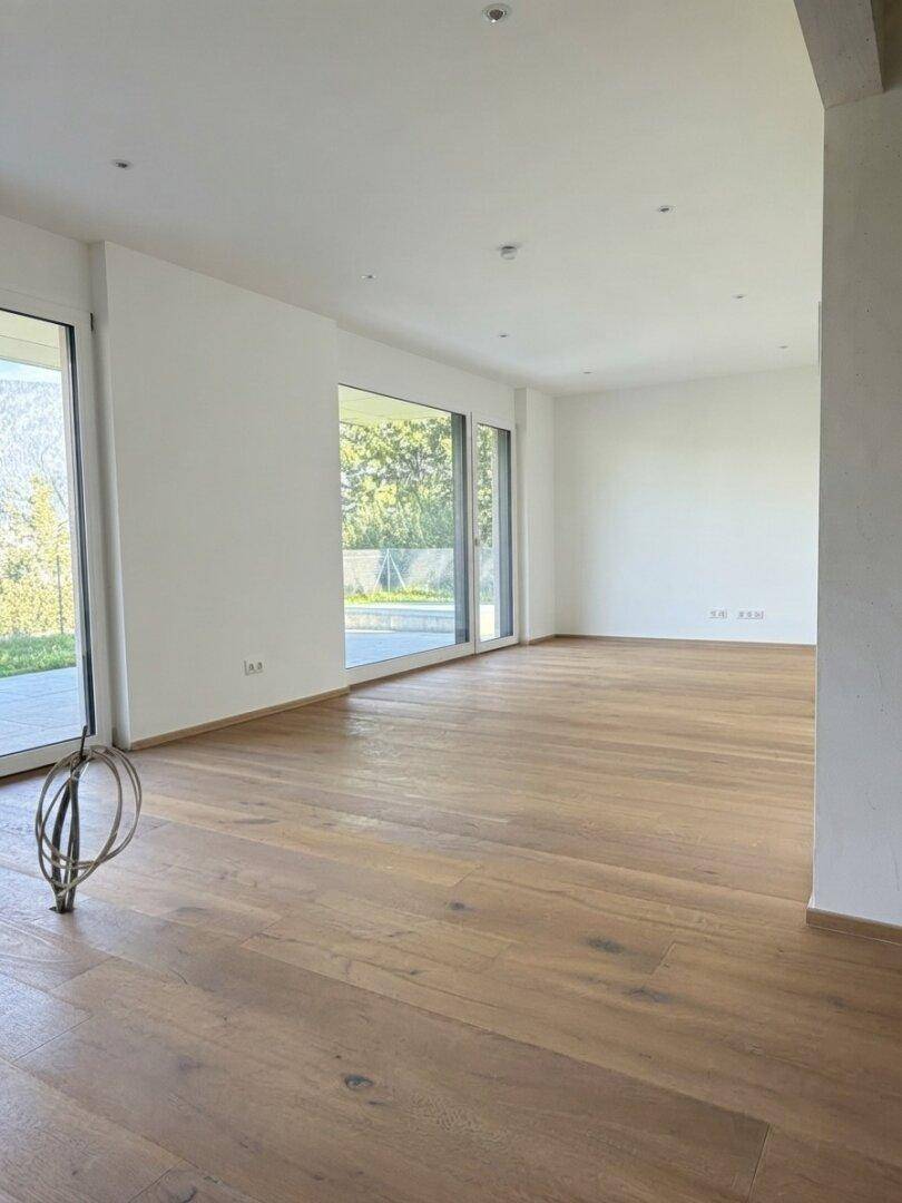Heller, leerer Raum mit Eichenparkettboden und großen Fenstern, die viel Tageslicht hereinlassen.