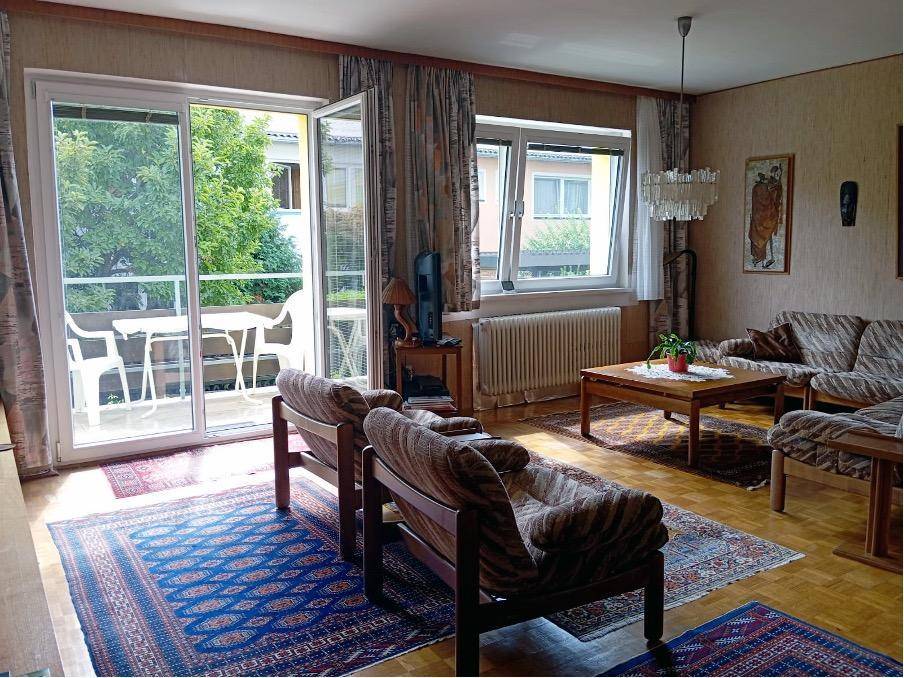 Gemütliches Wohnzimmer mit Zugang zum Balkon, Parkettboden und traditionellen Möbeln.