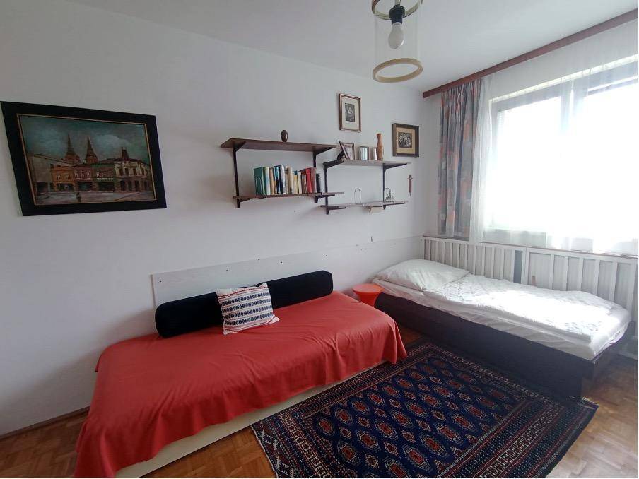 Helles Schlafzimmer mit zwei Betten, einem Fenster und praktischen Wandregalen.