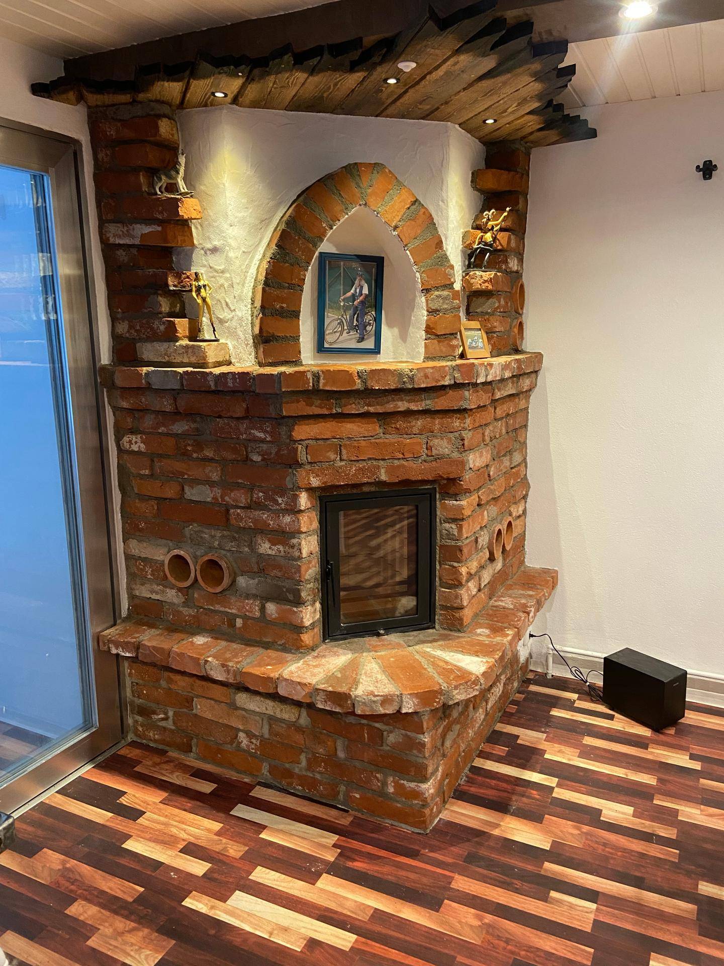 Gemauerter Kamin mit kleinem Fenster, in die Wand integriert, unter Holzbalken an der Decke.