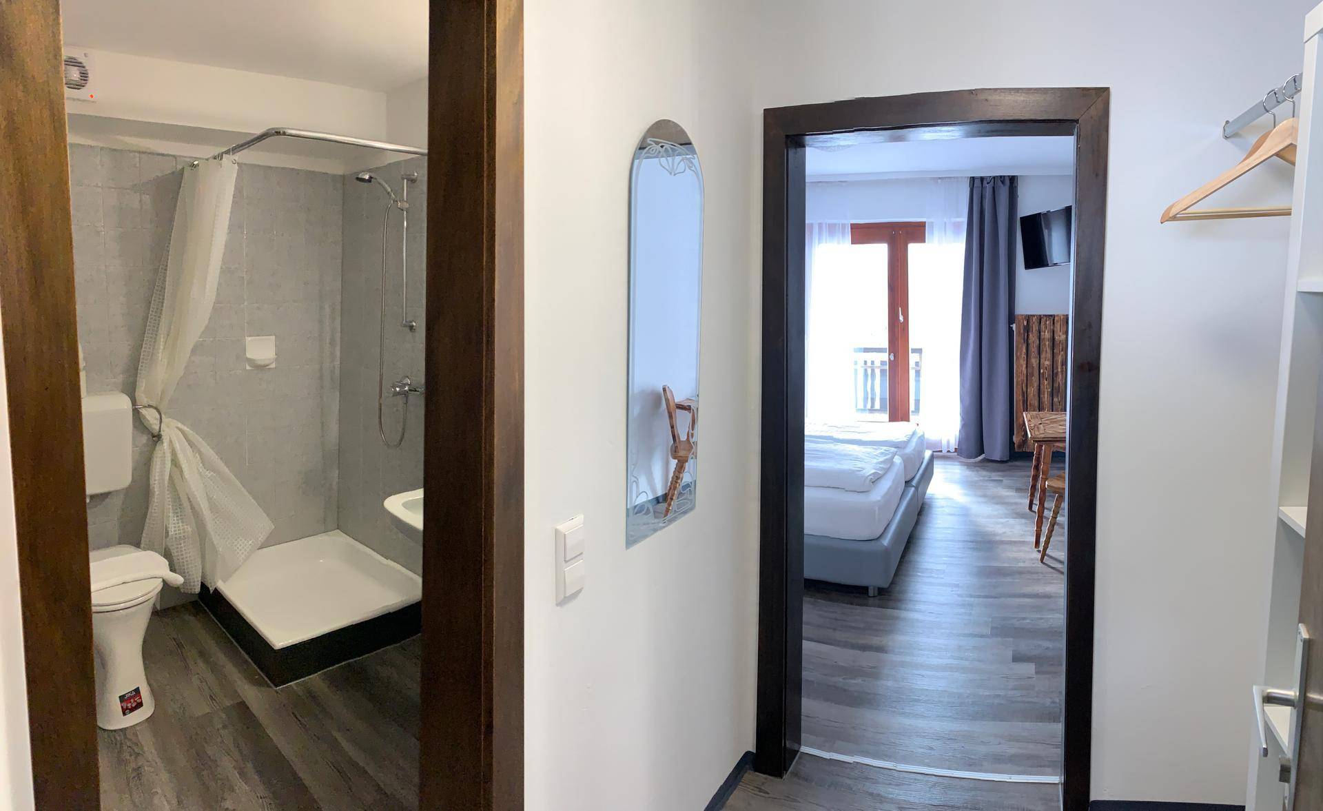 Flur, der zu einem Schlafzimmer und einem Badezimmer mit Dusche und Toilette führt.