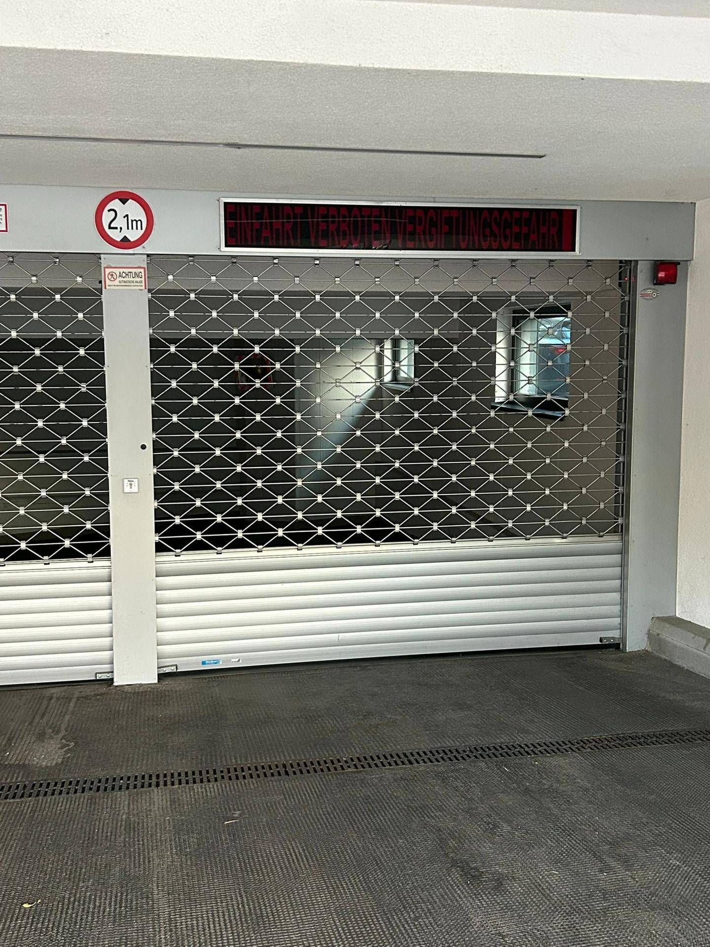 Einfahrt zur Tiefgarage mit Metallrollgitter und Höhenbegrenzung von 2,1 Metern.
