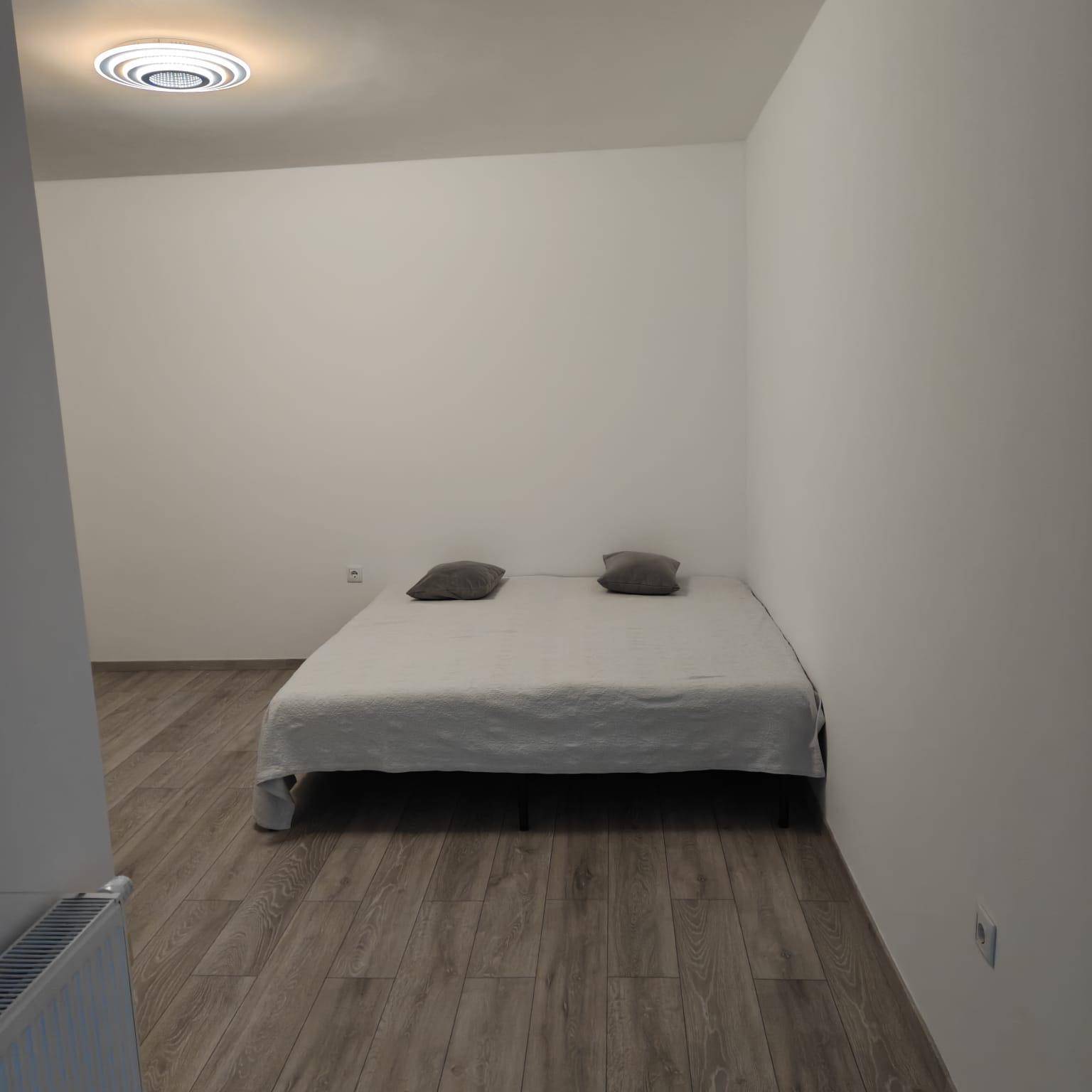 Schlafzimmer mit hellem Laminatboden und einem einfachen Bett, bereit zur Einrichtung.