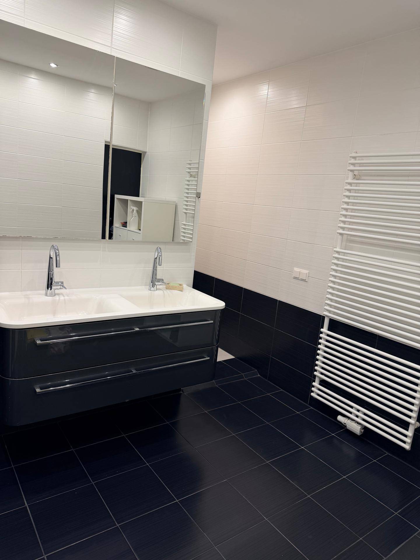 Modernes Badezimmer mit Doppelwaschbecken, großem Spiegel und beheiztem Handtuchhalter.