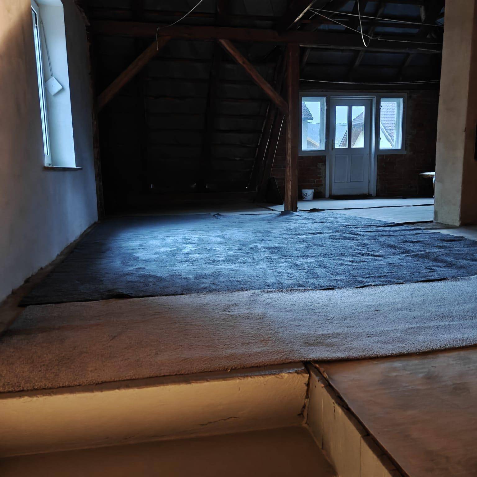 Unausgebauter Dachboden mit sichtbaren Holzbalken und Fenstern, bereit zum Ausbau.