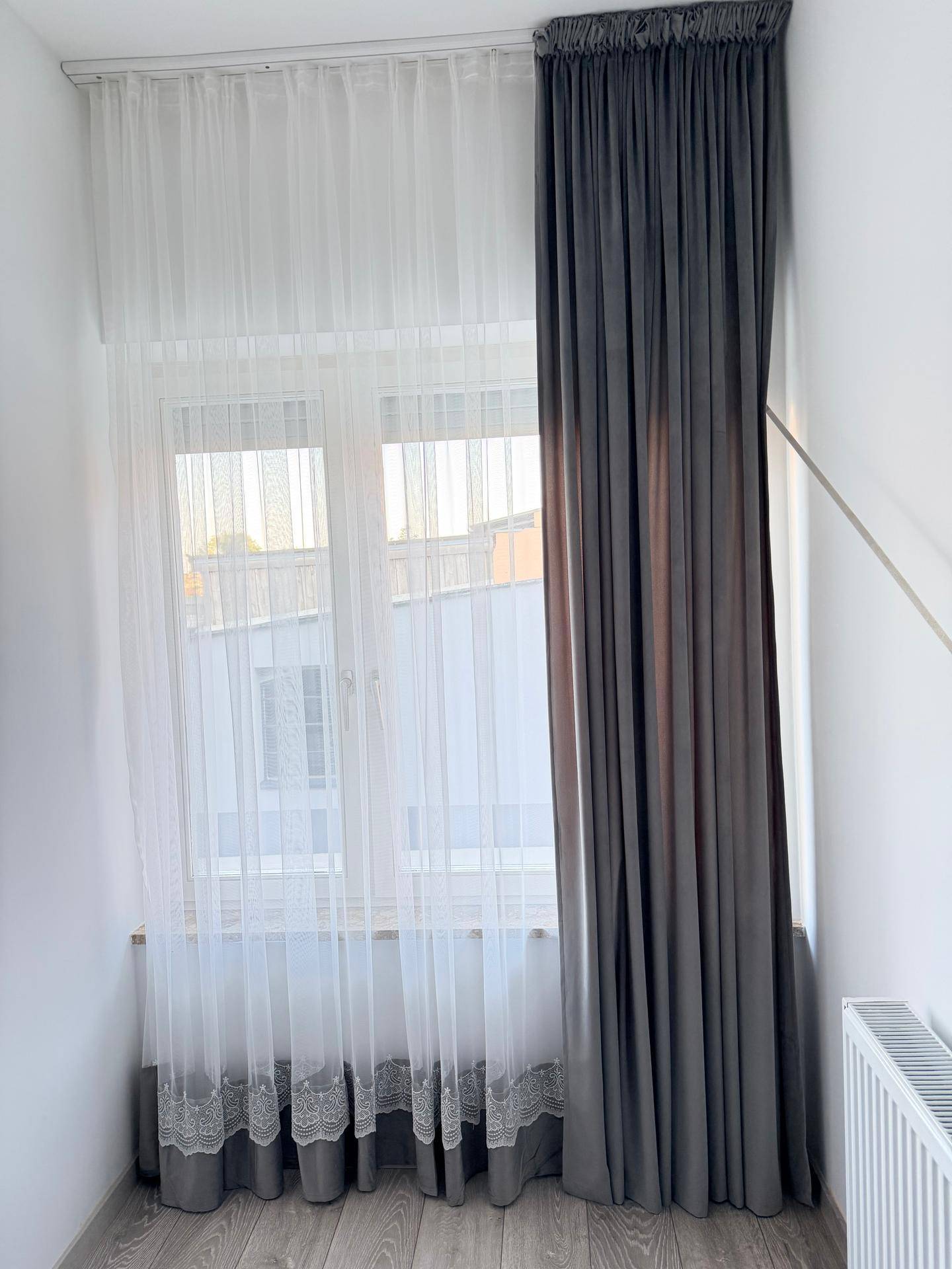 Schlafzimmer mit Fenster, weißen Gardinen und dunklen Vorhängen, bereit zur Einrichtung.