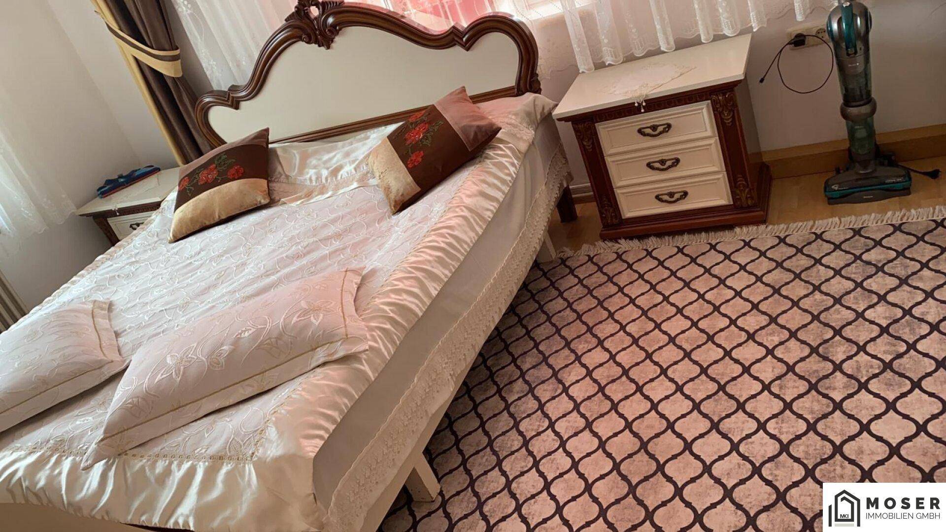 Klassisches Schlafzimmer mit großem Bett, Nachttischen und gemustertem Teppich.