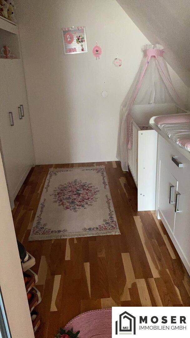 Kinderzimmer mit Babybett, Wickeltisch und Schrank auf Holzfußboden.