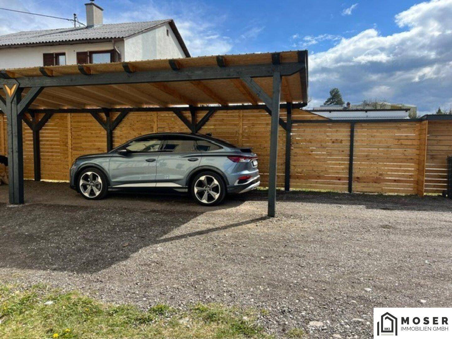 Neuer Carport mit Holzverkleidung bietet geschützten Stellplatz für ein Fahrzeug.