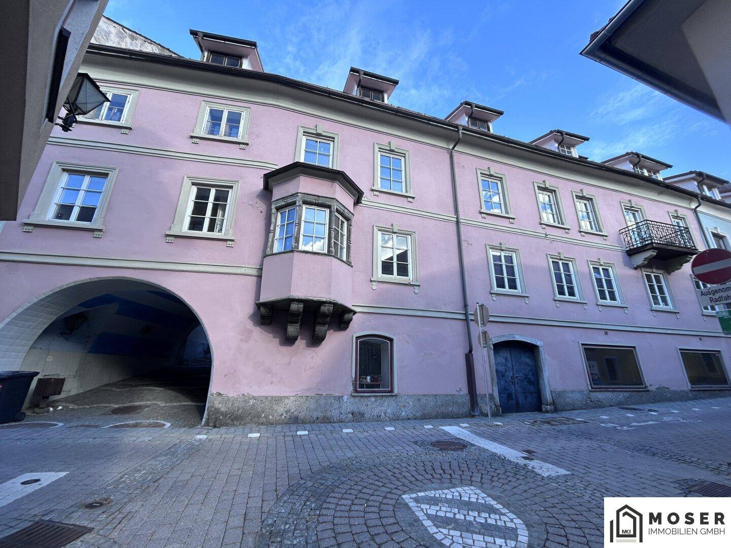 Rosa gestrichenes historisches Gebäude mit Erker, Bogenpassage und Kopfsteinpflaster in der Altstadt.