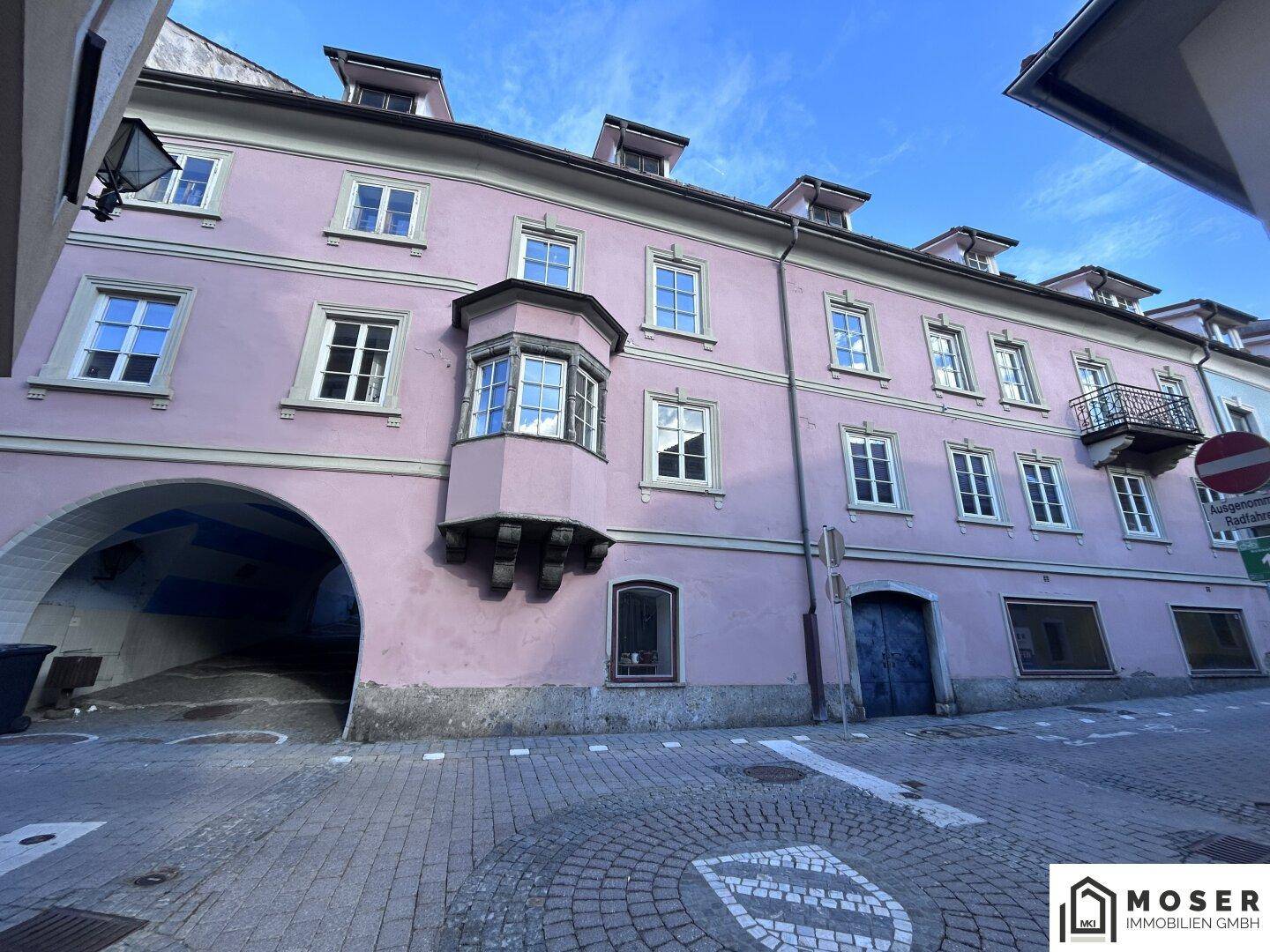Rosa gestrichenes historisches Gebäude mit Erker, Bogenpassage und Kopfsteinpflaster in der Altstadt.