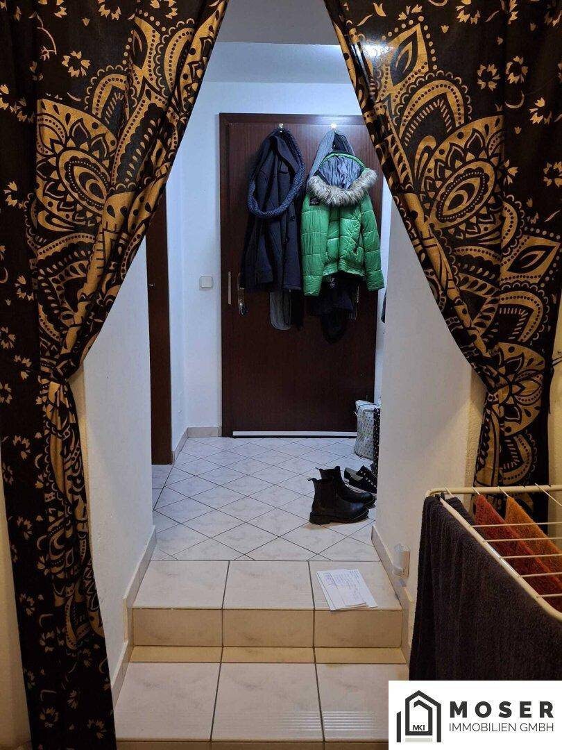 Eingangsbereich mit Fliesenboden, Garderobe und einem dekorativen Vorhang.
