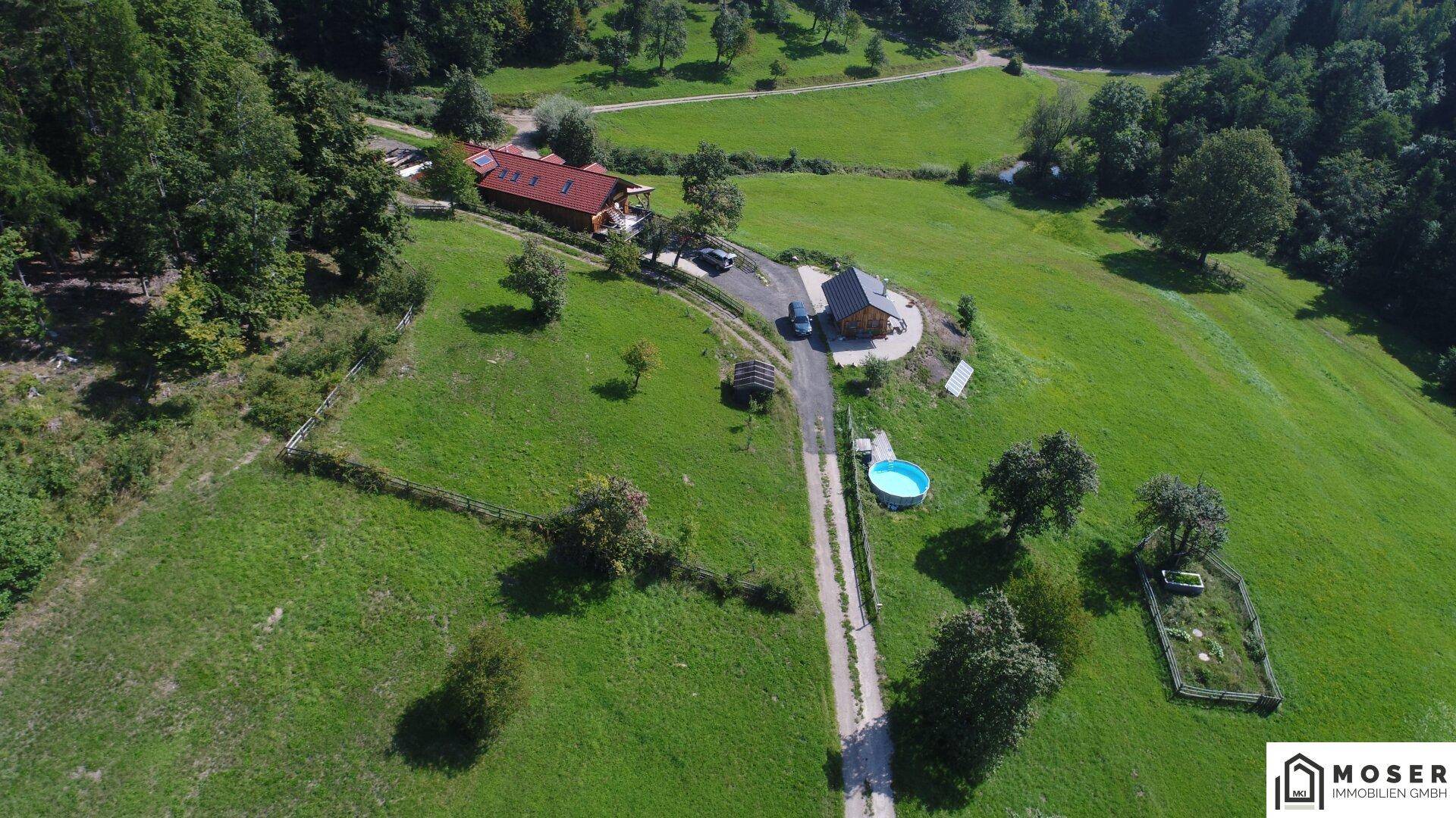 Luftaufnahme des Anwesens mit Haupthaus, Hütte, Pool und umzäuntem Gemüsegarten in ländlicher Umgebung.