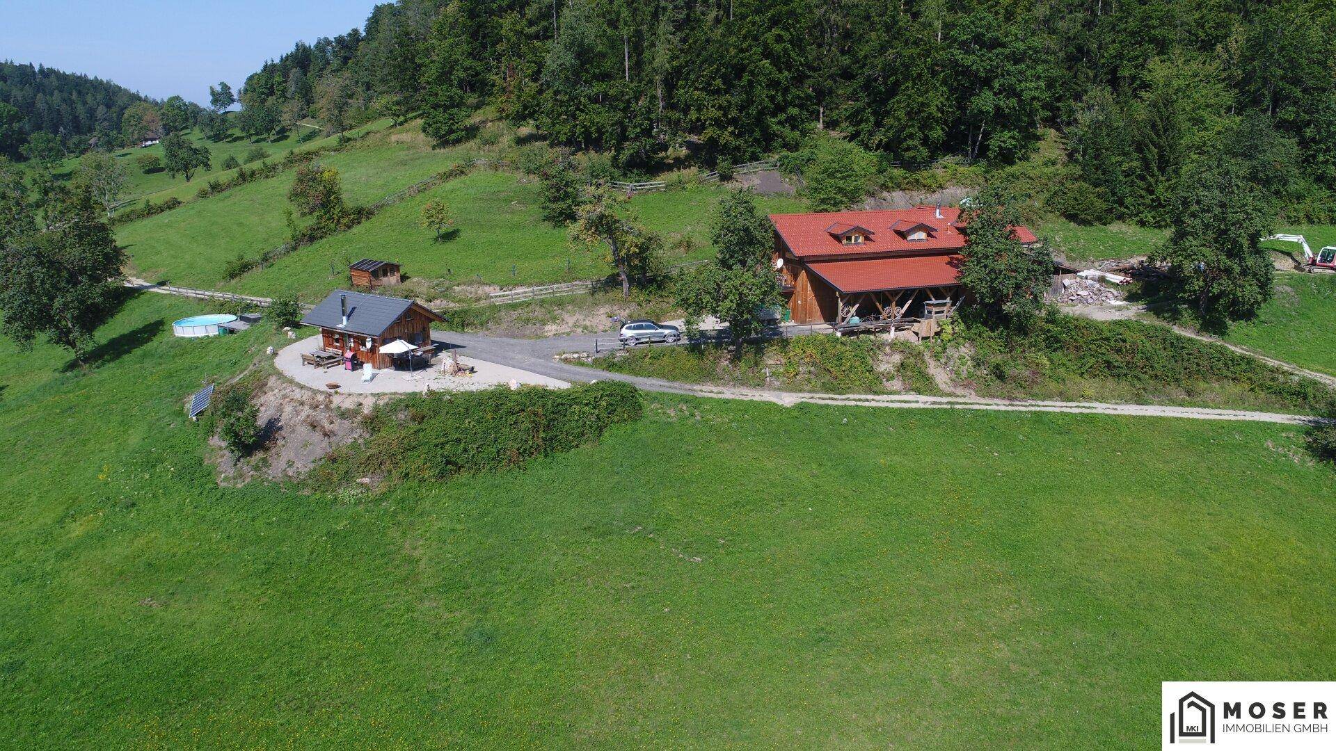 Luftaufnahme des Haupthauses und der Hütte, die die gesamte Anordnung des Anwesens am Hang zeigt.