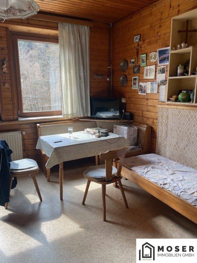 Gemütliches Zimmer mit Holzvertäfelung, Einzelbett und kleinem Tisch am Fenster.