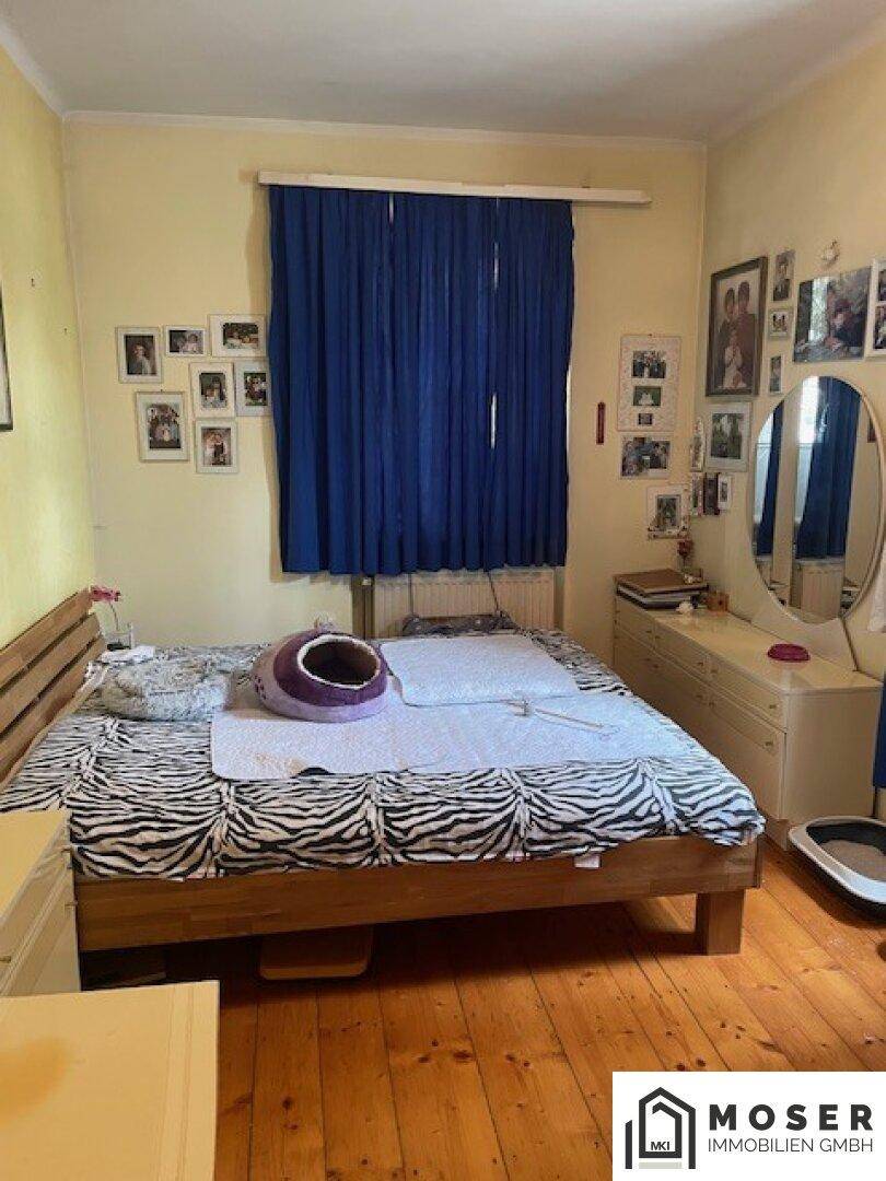 Schlafzimmer mit Holzbett, Zebra-Muster-Bettwäsche und gelben Wänden.