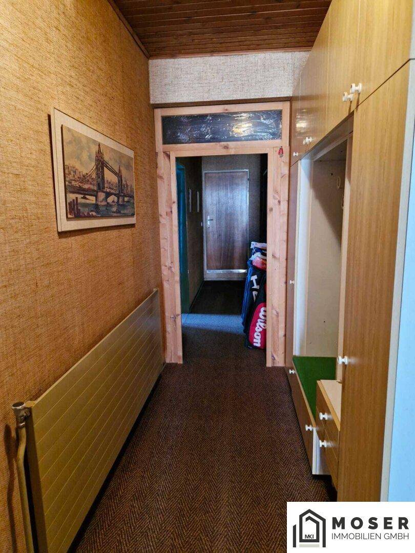 Schmaler Flur mit Teppichboden, Holzvertäfelung und einem Einbauschrank.