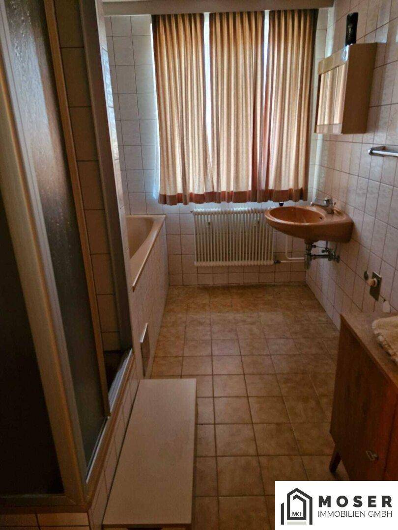 Badezimmer mit Badewanne, Dusche, Fliesenboden und einem Waschbecken aus Holz.