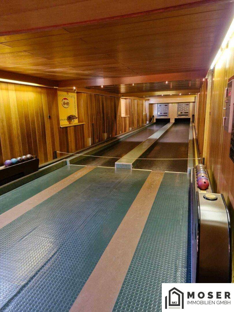 Lange Kegelbahn mit zwei Bahnen, holzvertäfelten Wänden und Decke für Freizeitaktivitäten.
