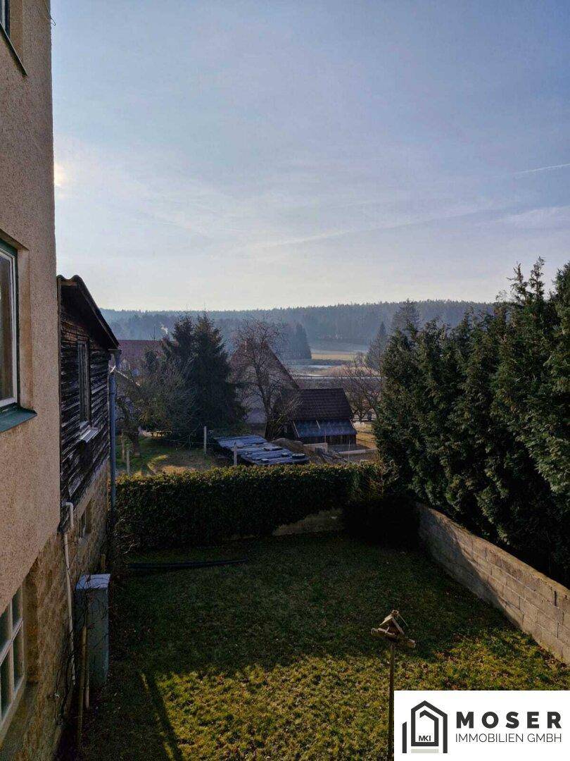 Kleiner Gartenbereich mit Rasenfläche und Bäumen, bietet einen weiten Blick in die Landschaft.