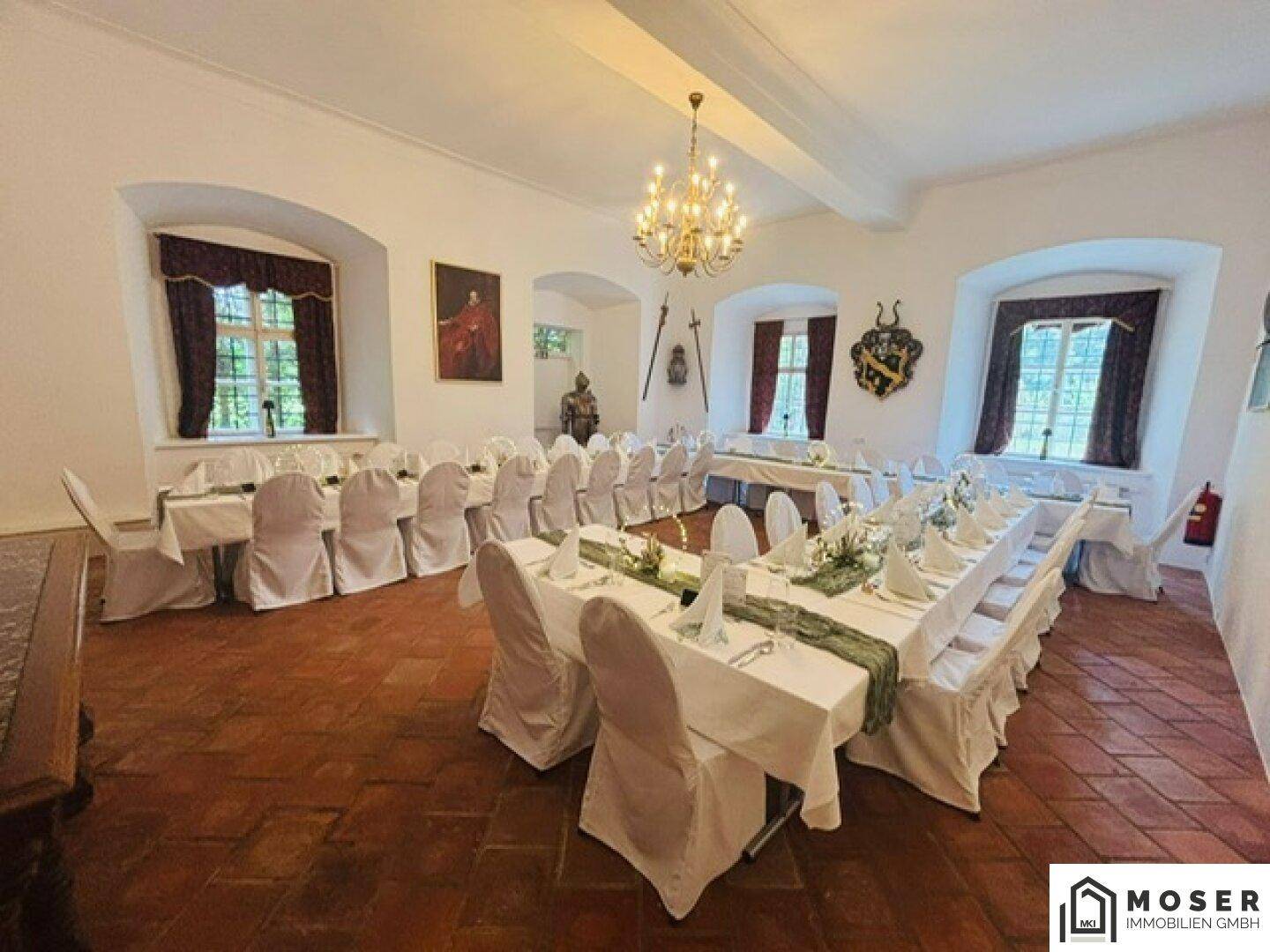 Festlich gedeckter Veranstaltungsraum mit langen Tischen, weißen Stuhlhussen und eleganten Dekorationen.
