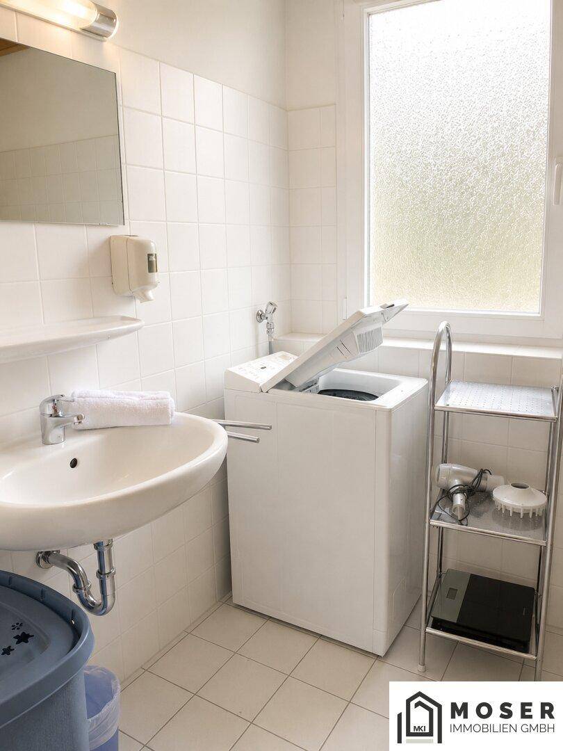 Praktischer Waschraum mit Waschbecken, Waschmaschine, Fliesenboden und einem Fenster für Belüftung.
