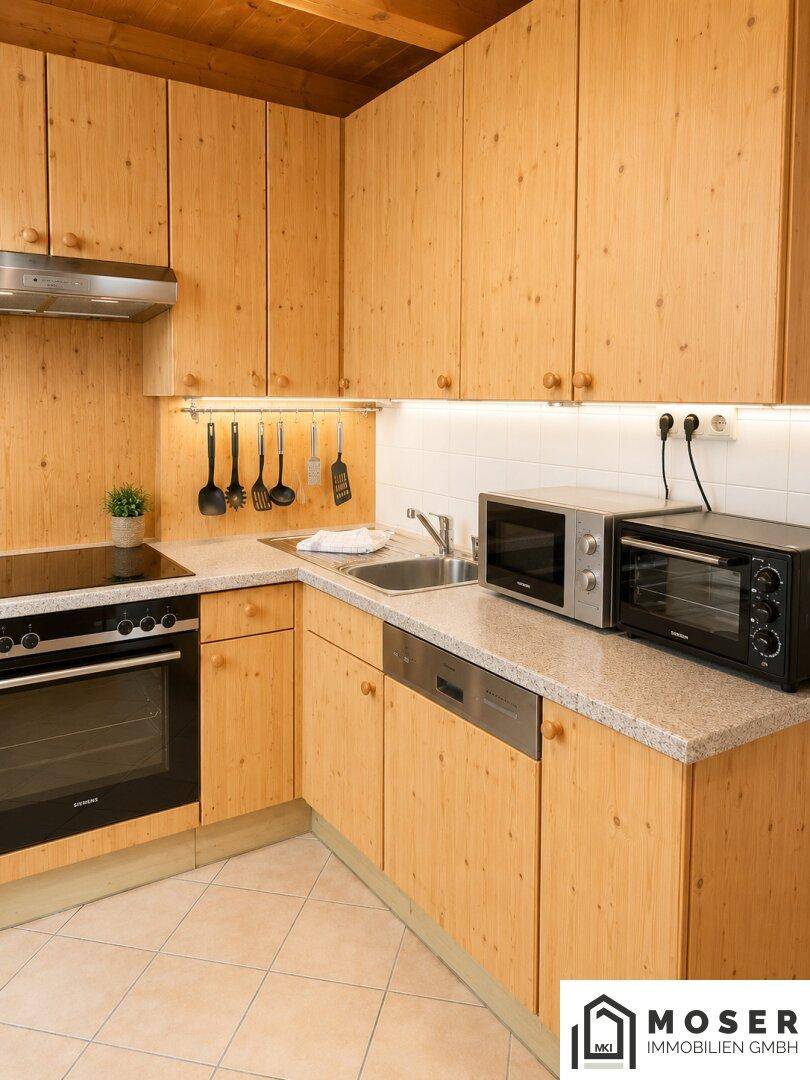 Voll ausgestattete Küche im Landhausstil mit Holzschränken, Granitarbeitsplatte und modernen Geräten.