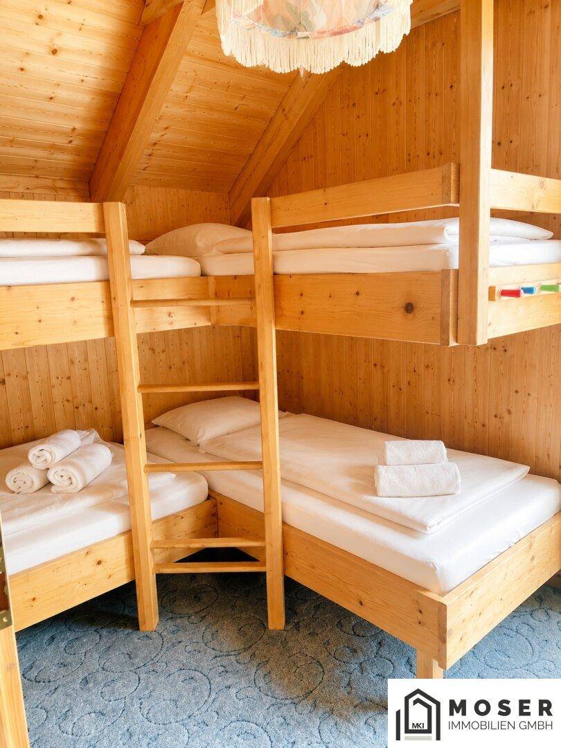 Kinderzimmer mit Etagenbetten, Holztäfelung und Dachschräge, ideal für Familien.