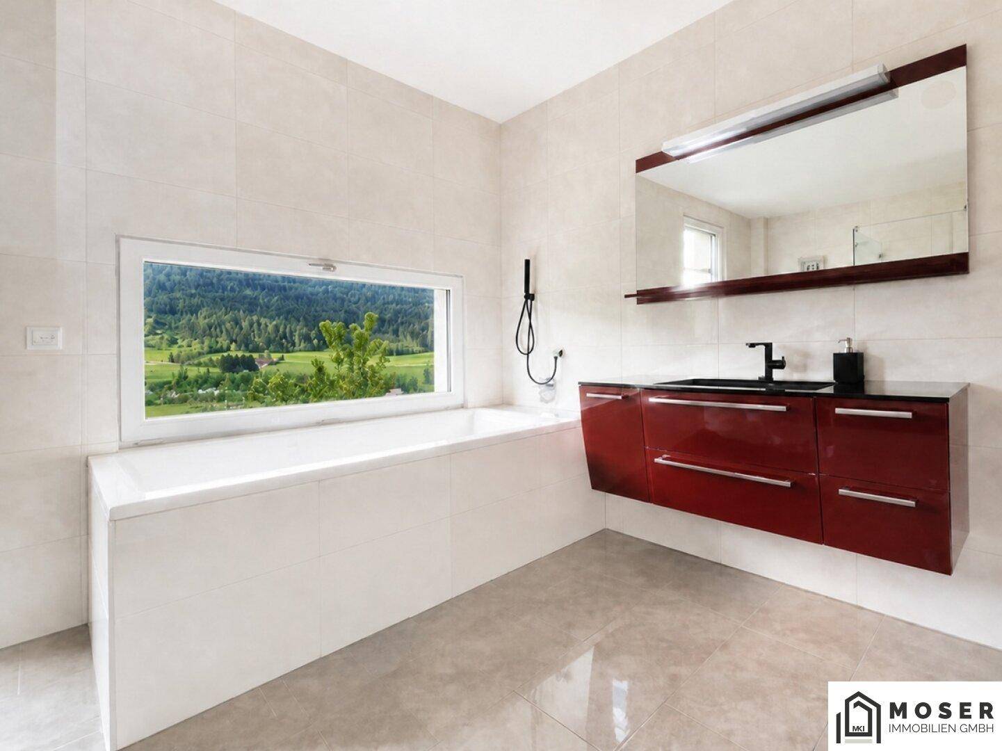 Modernes Badezimmer mit Badewanne, Waschtisch und großem Fenster mit Bergblick.
