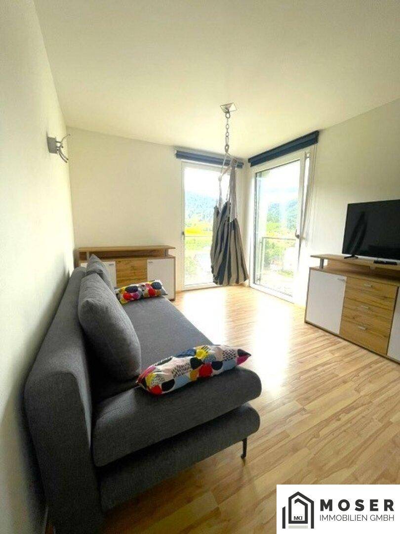 Heller Raum mit Sofa und Zugang zum Balkon, bietet eine entspannte Atmosphäre.