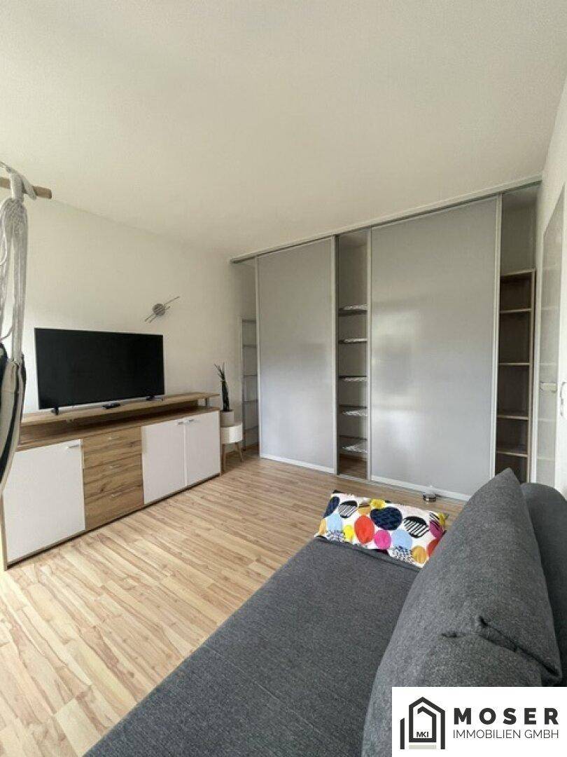 Heller Raum mit Sofa, TV-Möbel und integrierten Schränken, ideal als Gästezimmer.