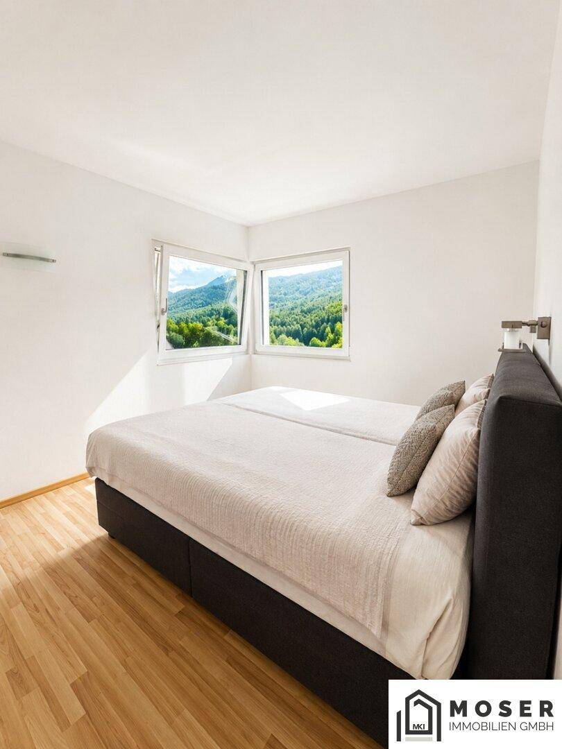 Gemütliches Schlafzimmer mit Doppelbett und Fenstern, die einen schönen Bergblick bieten.