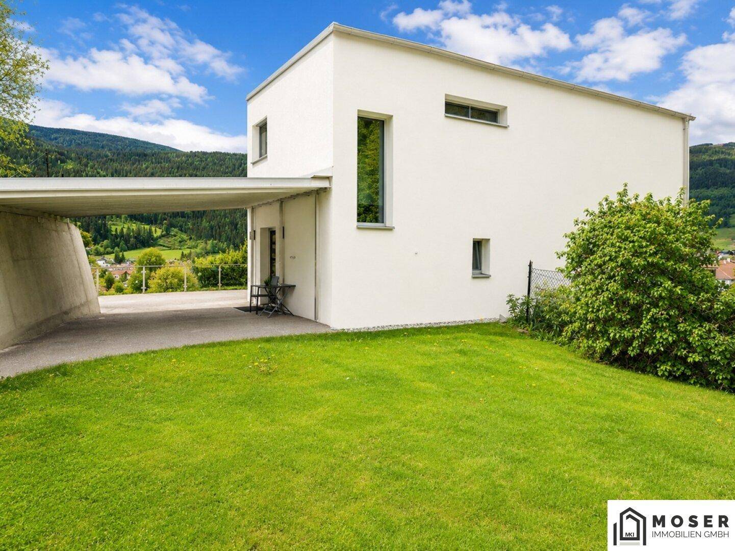 Seitliche Ansicht des Hauses mit gepflegtem Rasen und überdachtem Carport.