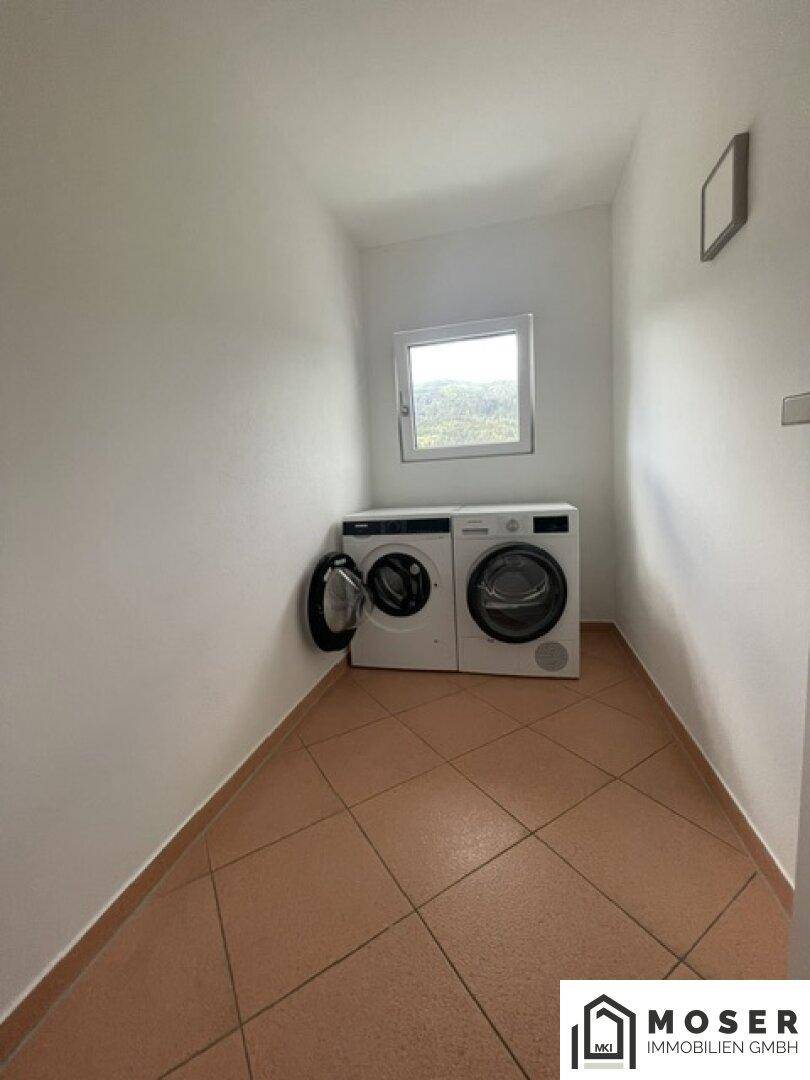 Praktischer Hauswirtschaftsraum mit Waschmaschine, Trockner und Fenster.