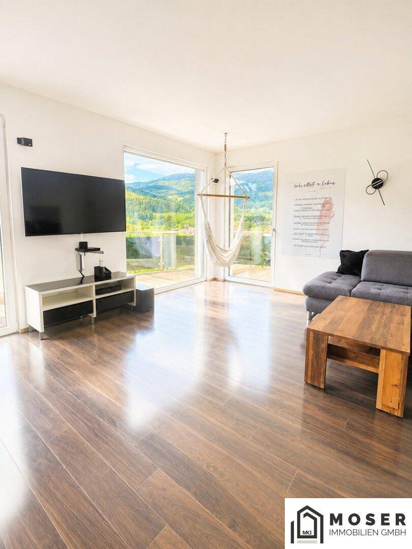 Helles Wohnzimmer mit großen Fenstern, die einen weiten Blick in die Natur bieten.
