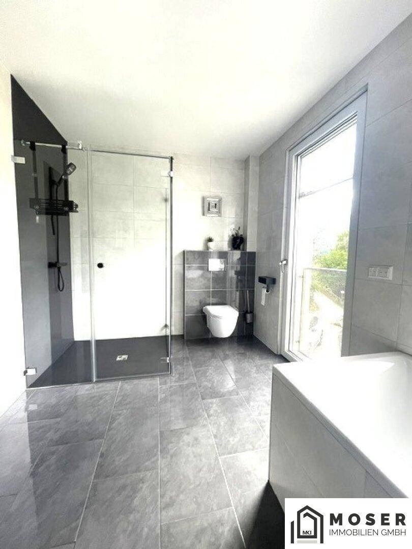 Helles Badezimmer mit ebenerdiger Dusche, WC und Zugang zu einem Außenbereich.
