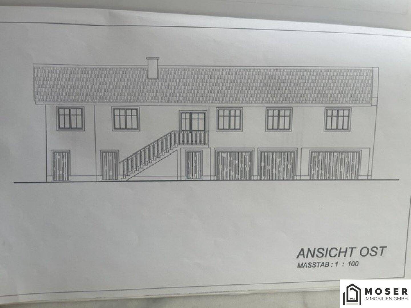 Ostansicht des Gebäudes mit mehreren Fenstern und Garagentoren im Erdgeschoss.