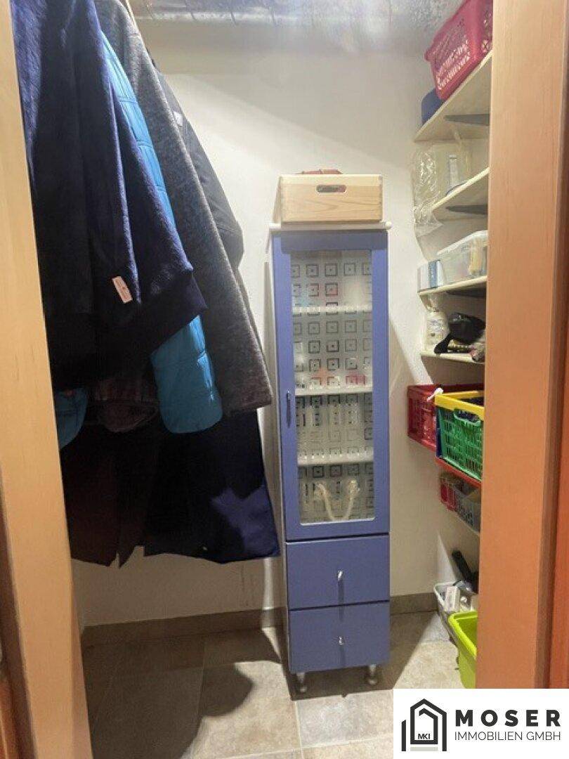 Praktischer Abstellraum mit Kleiderstange, Regalen und einem kleinen Schrank.