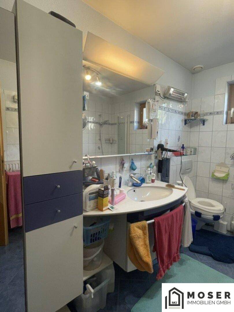 Badezimmer mit großem Spiegel, Waschbecken und Stauraum unter dem Waschtisch.