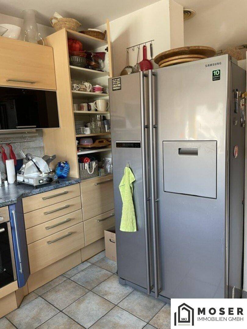 Geräumige Küche mit großem Kühlschrank, Holzschränken und praktischen Ablageflächen.