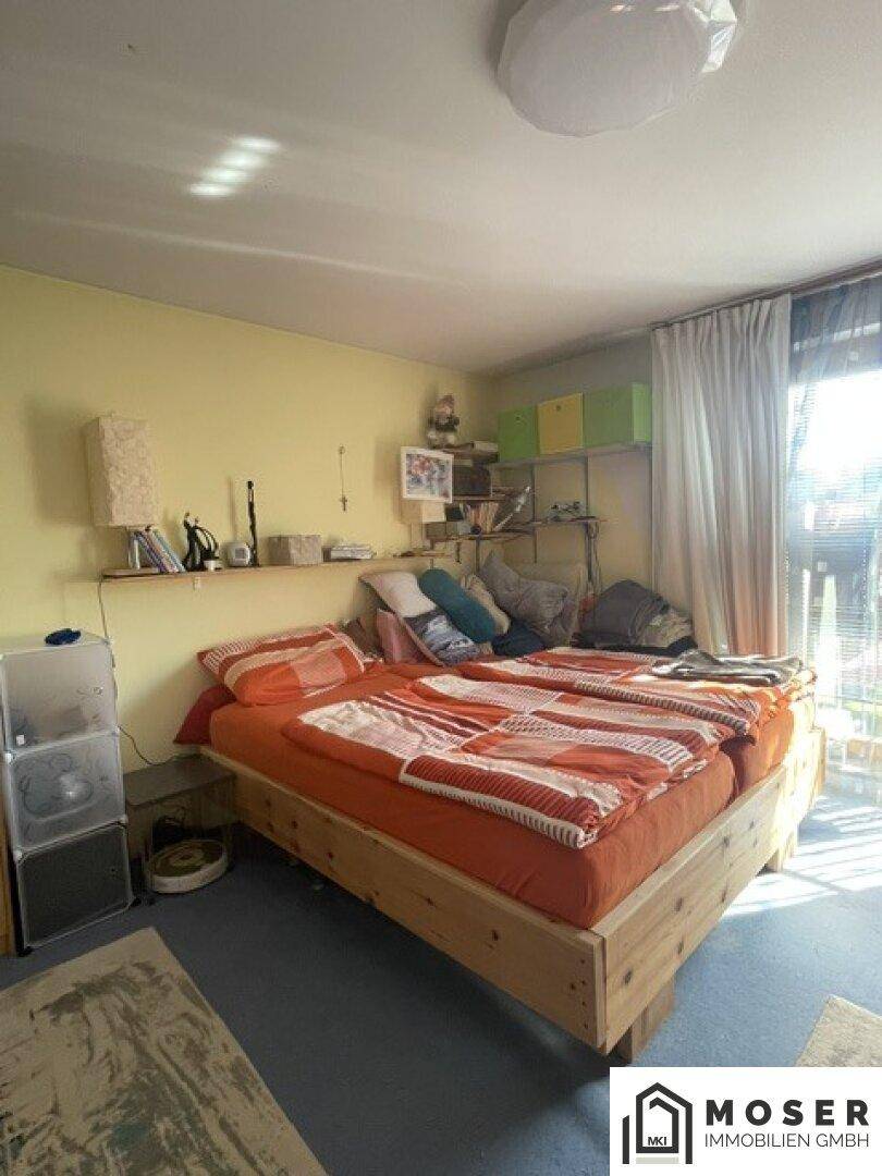 Helles Schlafzimmer mit zwei Betten, gelben Wänden und Teppichboden, gut beleuchtet durch das Fenster.