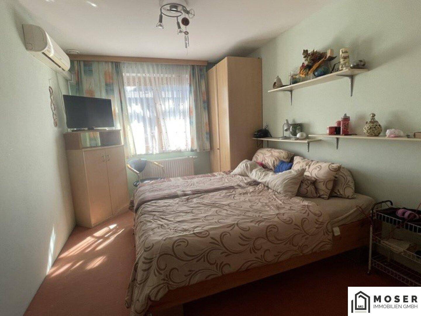 Gemütliches Schlafzimmer mit zwei Betten, Klimaanlage und Teppichboden, hell durch das Fenster.